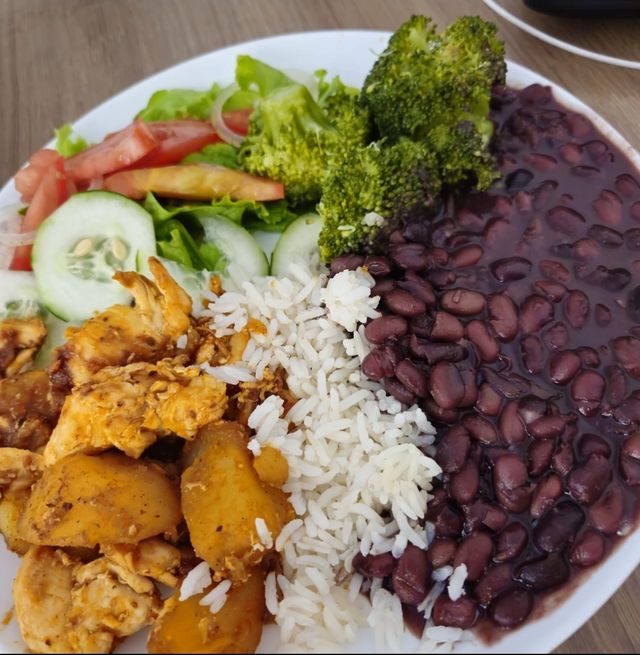 Prato com frango e batata, arroz, feijão preto, brócolis e salada