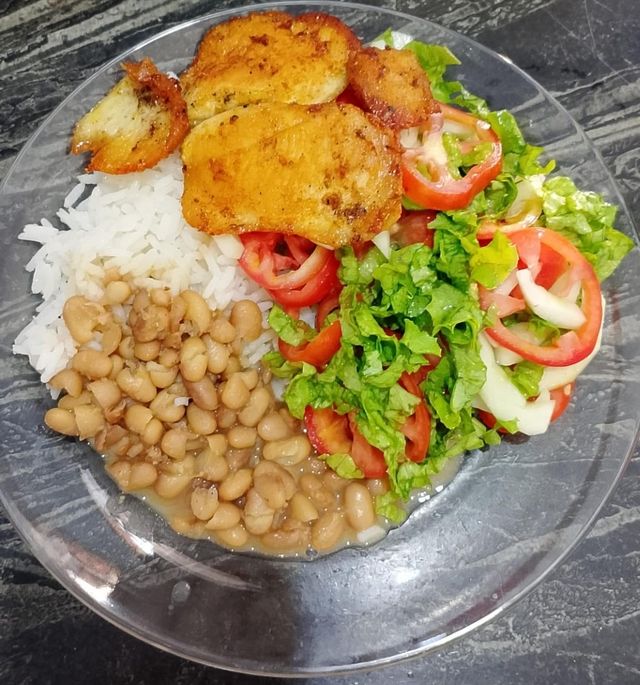 Prato com peixe, arroz, feijão e salada de alface e tomate