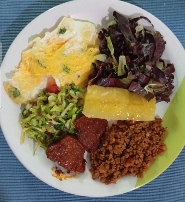 Prato com omelete, aipim, carne de soja, repolho e alface roxa